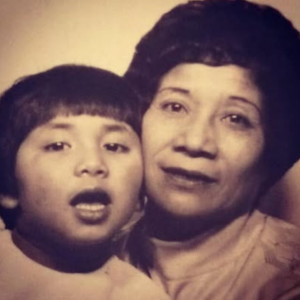 A young Christina Vaughan and her mum. The image is in sepia tones - Christina is on the left and gher mum is on the right. They are smiling.